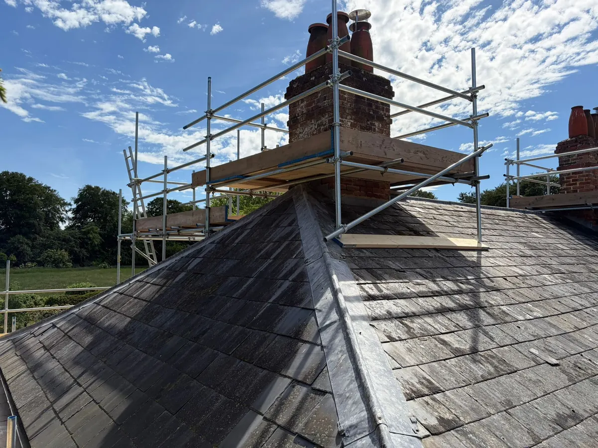 Scaffold built around a brick chimney on a slate roof