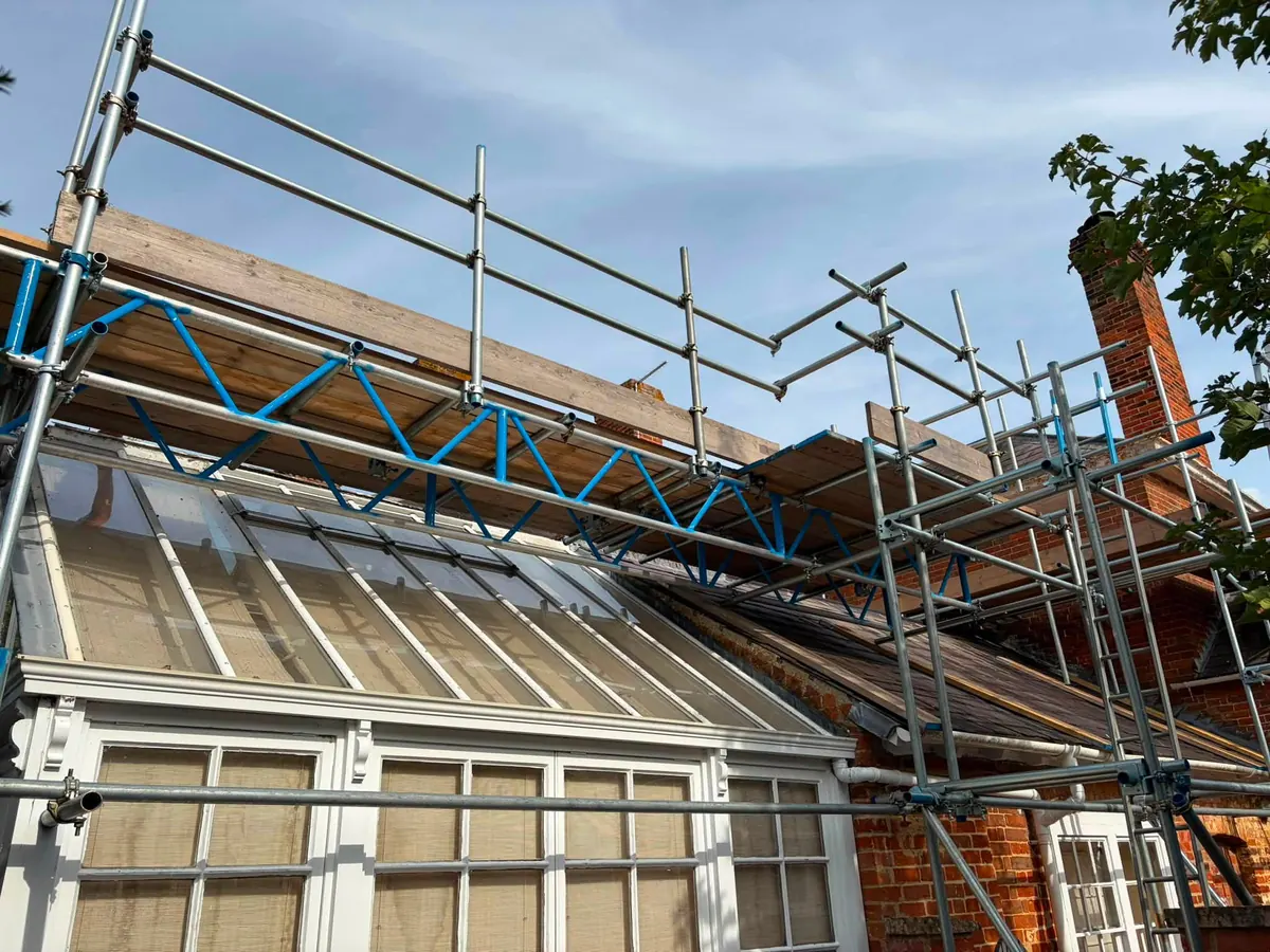 Beamed scaffold bridging a conservatory roof