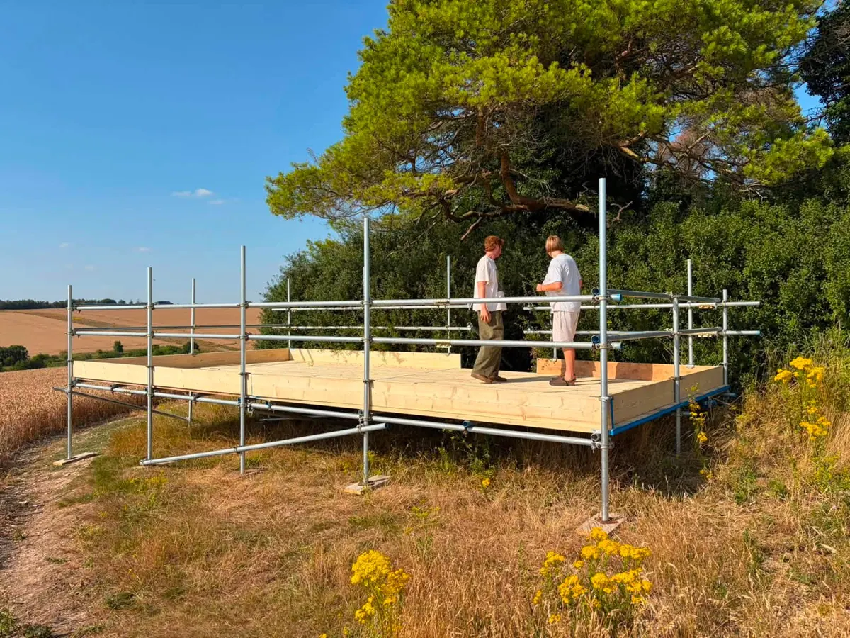 A free-standing boarded scaffold platform in a field