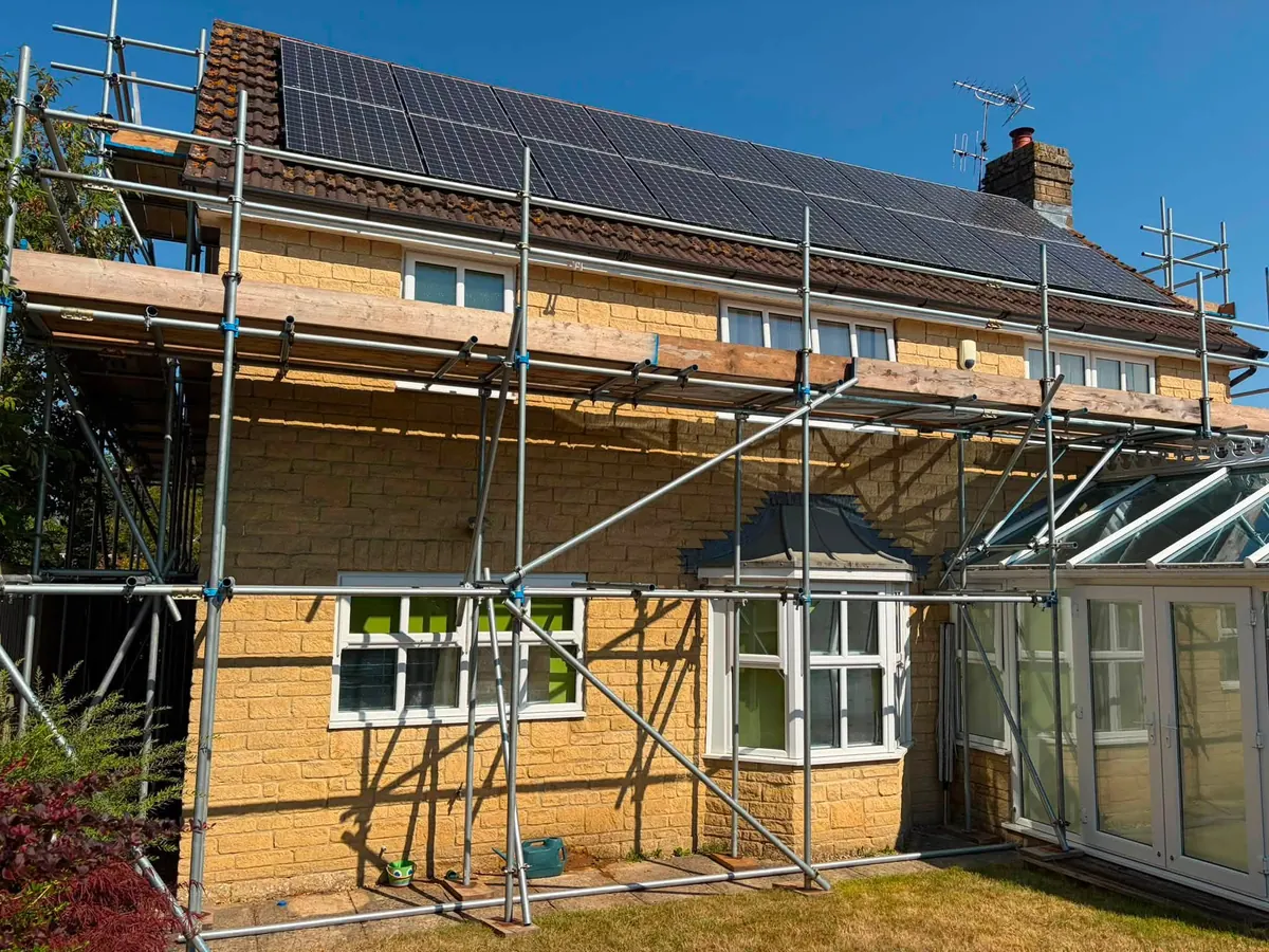 Scaffold to the eaves of a house with solar panels on the roof